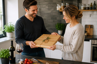 Paar in der Küche mit einem verschnürten Holz-Schneidebrett als Geschenk für Hobbyköche